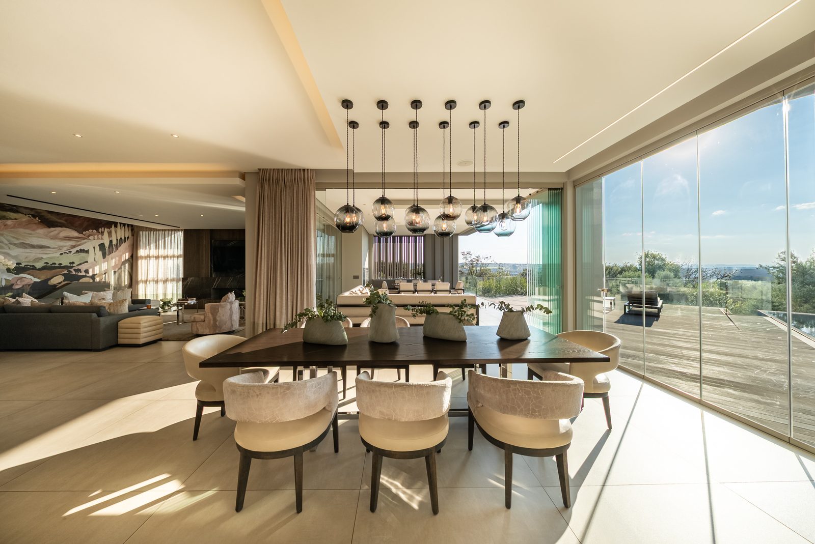 Dining room beneath a cluster of glass pendants, parkland beyond